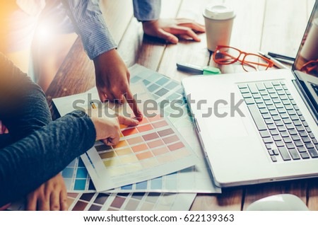 Graphic designer architects who work with laptops and color comparison tables for design work.