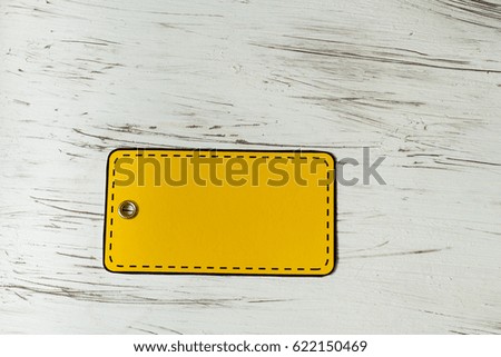 An empty yellow price tag on the background of an old white board. Country style. Selective focus.