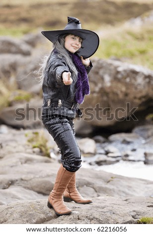Halloween picture - girl in a suit of a witch in a black hat on the nature