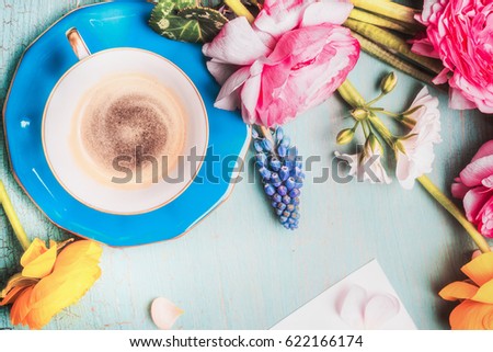 Cup of coffee and flowers on blue vintage shabby chic background, top view, copy space. Summer Breakfast