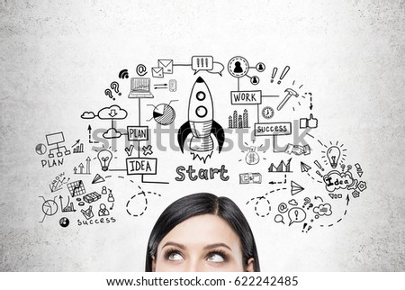 Close up of a head of a woman with black hair standing near a concrete wall with a rocket sketch drawn on it. Royalty-Free Stock Photo #622242485
