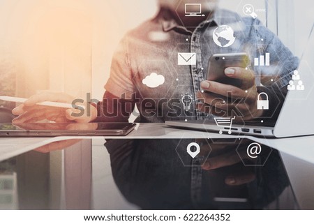 businessman working with mobile phone and laptop computer on wooden desk in modern office with virtual icons interface
