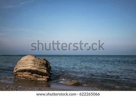 Stones on coast of blue sea, blue sky. Rock and sea .