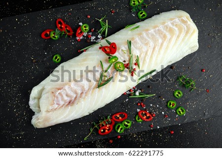 Fresh Raw Cod loin fillet with rosemary, chillies, cracked pepper on stone board