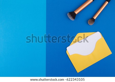 Beauty background. Make up brushes and yellow envelope with blank card. Top view. Flat lay.