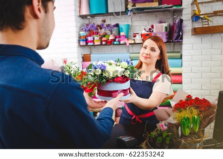 attractive young girl working in a flower shop. A man buys flowers from florists. flower shop