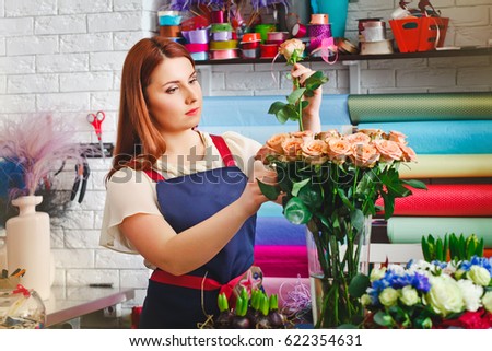 attractive young girl working in a flower shop, The flower-seller in the flower shop makes bouquets of roses. florist