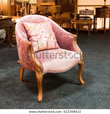 Classic armchair with a cushion in a furniture store. Beautiful pink armchair in the interior of a shop.