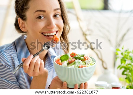 Closeup of a woman eating healthy salad with tomatoes cherry indoors