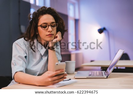 Bored young woman using smartphone in the library