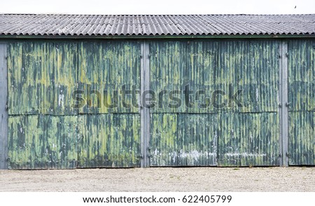 horizontal picture of rusty corrugated iron doors of shed with green yellow paint