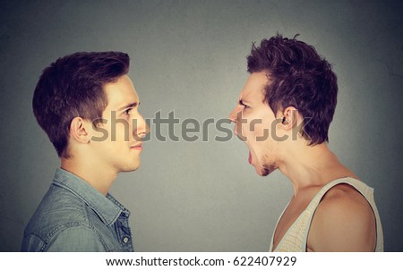 Side profile portrait of young angry man screaming at a calm smiling guy 