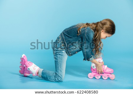 little girl in pink roller skates in studio on blue