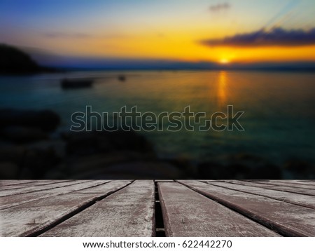 Wooden floor with blurred  nature view of the sea and boat when sun set in the background