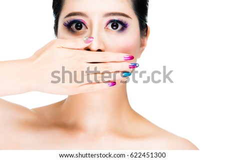 colorful and make up concept with young lady with hand on her face covering mouth. copyspace trendy woman with prefect skin and nail art and makeup.