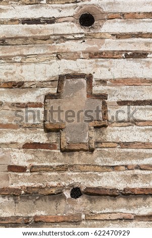 Cross on the wall of an ancient masonry. Backgrounds