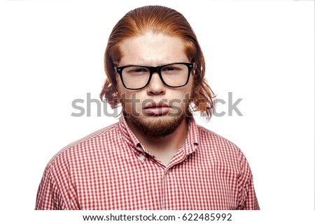 Thoughtful thinking bearded readhead businessman with red shirt and freckles and glasses looking at camera. studio shot isolated on white.
