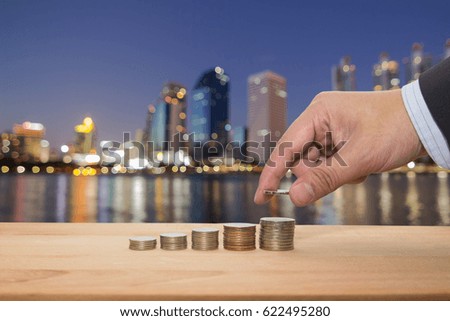 Saving money concept putting money coin stack and bokeh building background