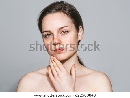 Young beautiful freckles woman with hands face portrait with healthy skin. Gray background.