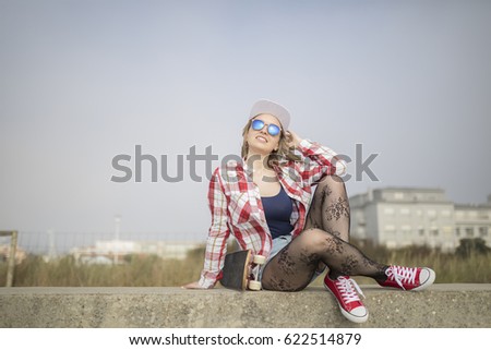 Beautiful and fashion young woman posing with a skateboard next to the beach