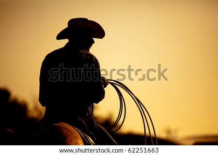 cowboy with lasso silhouette at small-town rodeo. Buyers note: image contains added grain to enhance theme of image. Royalty-Free Stock Photo #62251663