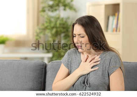 Woman suffering respiration problems sitting on a couch in the living room at home Royalty-Free Stock Photo #622524932