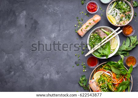 Assorted asian dinner with vietnamese noodle soup pho bo, pho ga, spring rolls, vegetable salad, copy space Royalty-Free Stock Photo #622543877