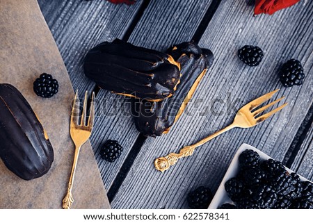 Delicious chocolate eclairs with berries on a grey wooden table.