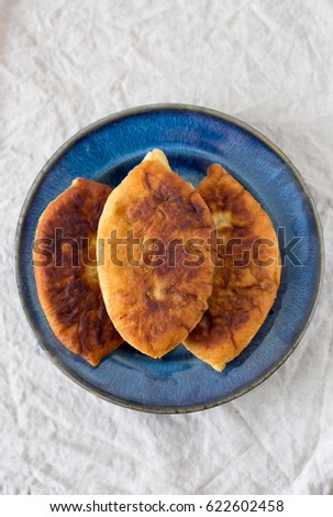 Traditional Homemade Baked Patties or Pies with Jam on blue dish. Fried Russian Pirozhki made from Yeast Dough in Rustic Style