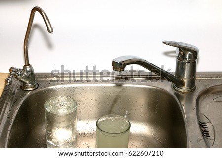 Filling a glass of clean and muddy water from a filter and a kitchen faucet