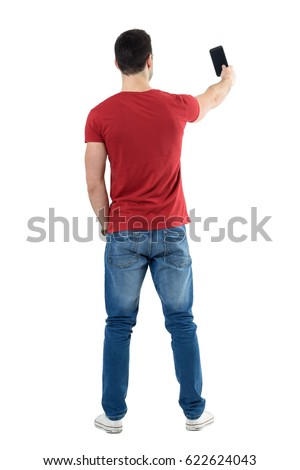 Backside view of young casual man taking photo with mobile phone. Full body length portrait isolated over white studio background.