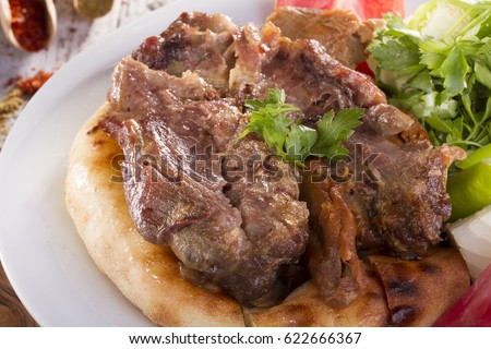 Turkish and Arabic Traditional Ramadan Lamb Meat Tandir serving with special bread, parsley, onion and tomato on rustic wood background. Royalty-Free Stock Photo #622666367