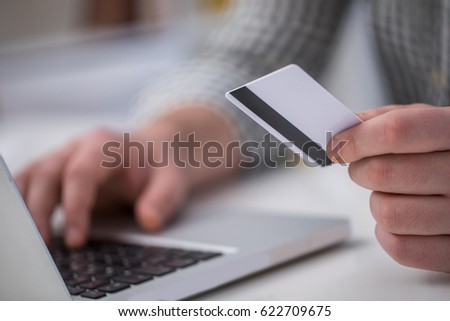 Using laptop for online shopping in office with credit card close up and cropped photo