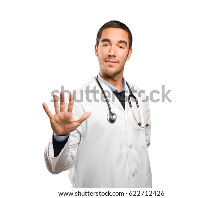 Confident doctor with keep calm gesture against white background