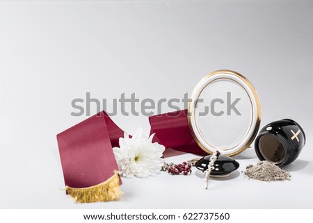 black urn with red tape,white chrysanthemum, rosary for sympathy card on bright background