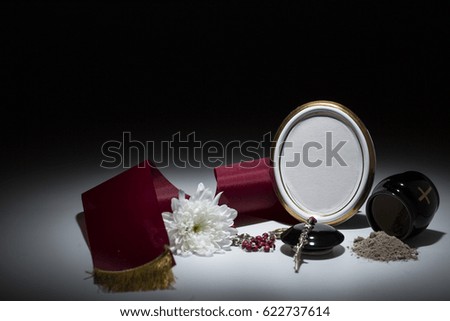black urn with red tape,white chrysanthemum, rosary for sympathy card on background