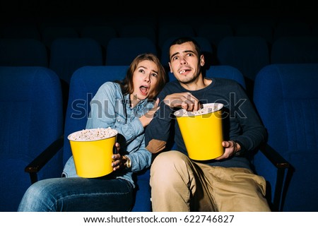 Couple of friends looking horror movie in cinema