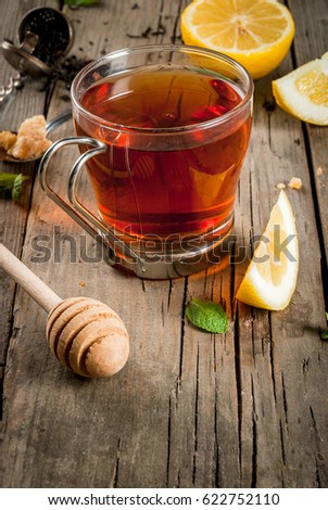 Autumn. Relaxation. English homemade tea. Fragrant black tea with organic mint, brown cane sugar, lemon and honey. On a wooden rustic table. Copy space