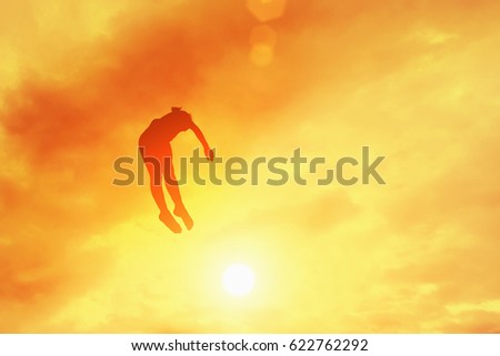 Silhouette of a girl jumping on a trampoline on a sky background. Toned