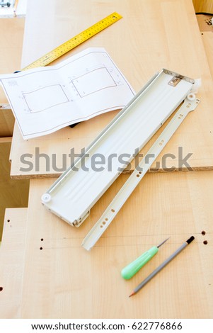 metal furniture fittings and drawings lies on chipboard sheet