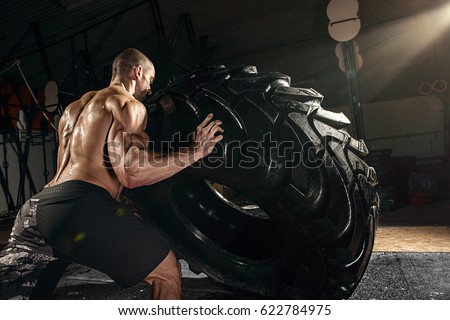 muscle cross strongman training - man flipping big tire Royalty-Free Stock Photo #622784975