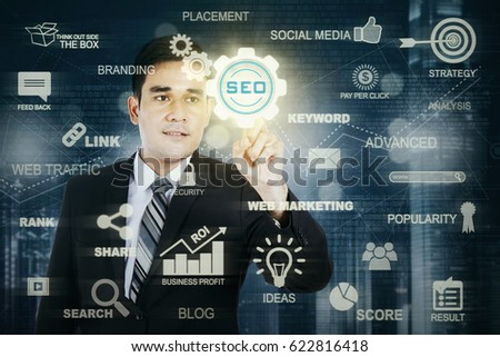 Photo of a male entrepreneur pressing a virtual SEO button on the futuristic screen. SEO concept