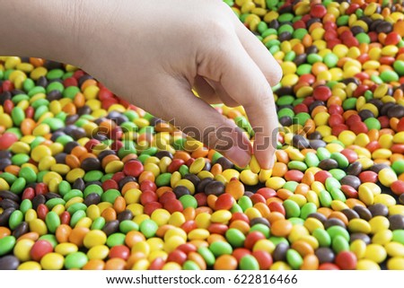 Picture of hand of a child picking up colorful candies