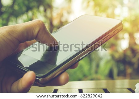Close-up of hand-holding mobile phone device online working  with sunset light background