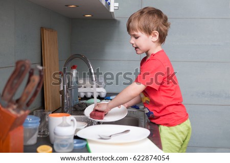 A little cute boy washing dishes in the white kitchen interior. casual lifestyle photo series in real life interior. Child with helping his parents with housework.
 Royalty-Free Stock Photo #622874054