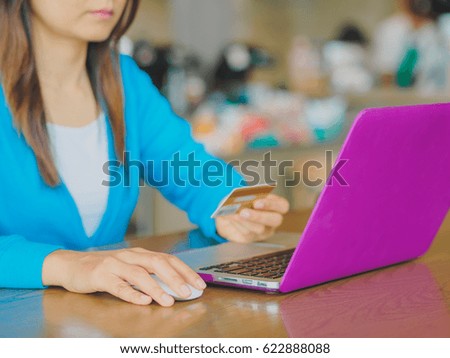 Pretty Young womans hands holding a credit card and using tablet, smartphone and laptop computer for online shopping. Online payment. Female working on smart phone laptop in a cafe.