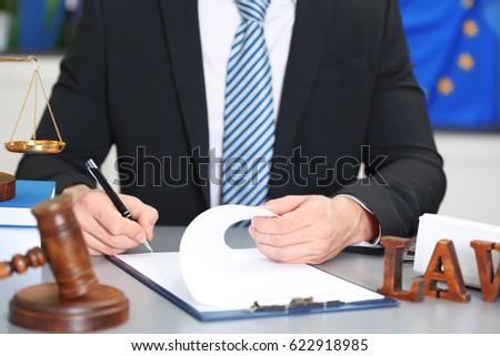 Male judge working with document and law accessories on table