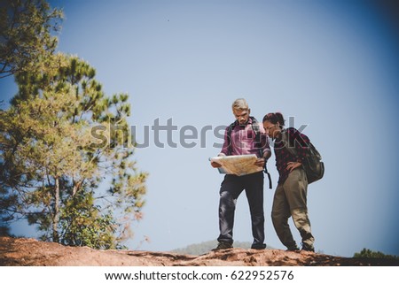 Young tourist couple traveling on holidays in mountain looking at map in search of attractions. Travel concept.