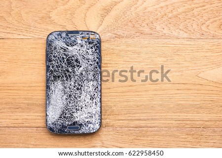 Top view broken of black smart phone on wooden table background