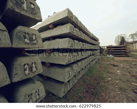 Sleepers stock in railway depot. New concrete railway ties stored for reconstruction of old railway station. Old houses  in background